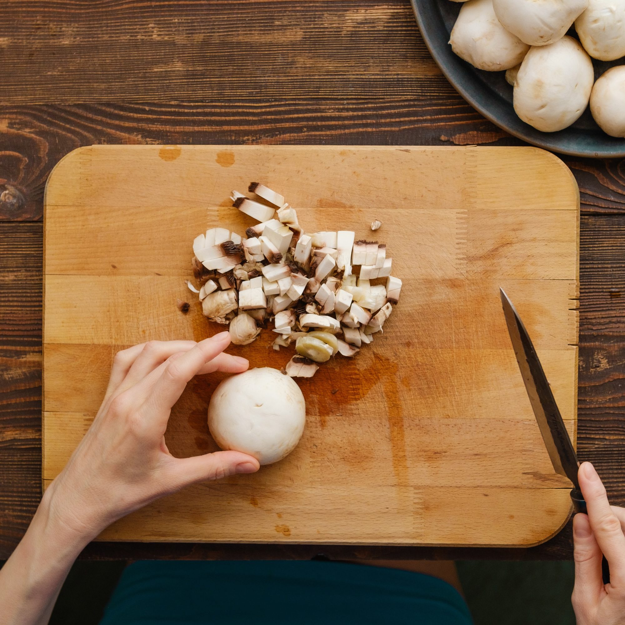 Unrecognizable woman chopping mushrooms, top view