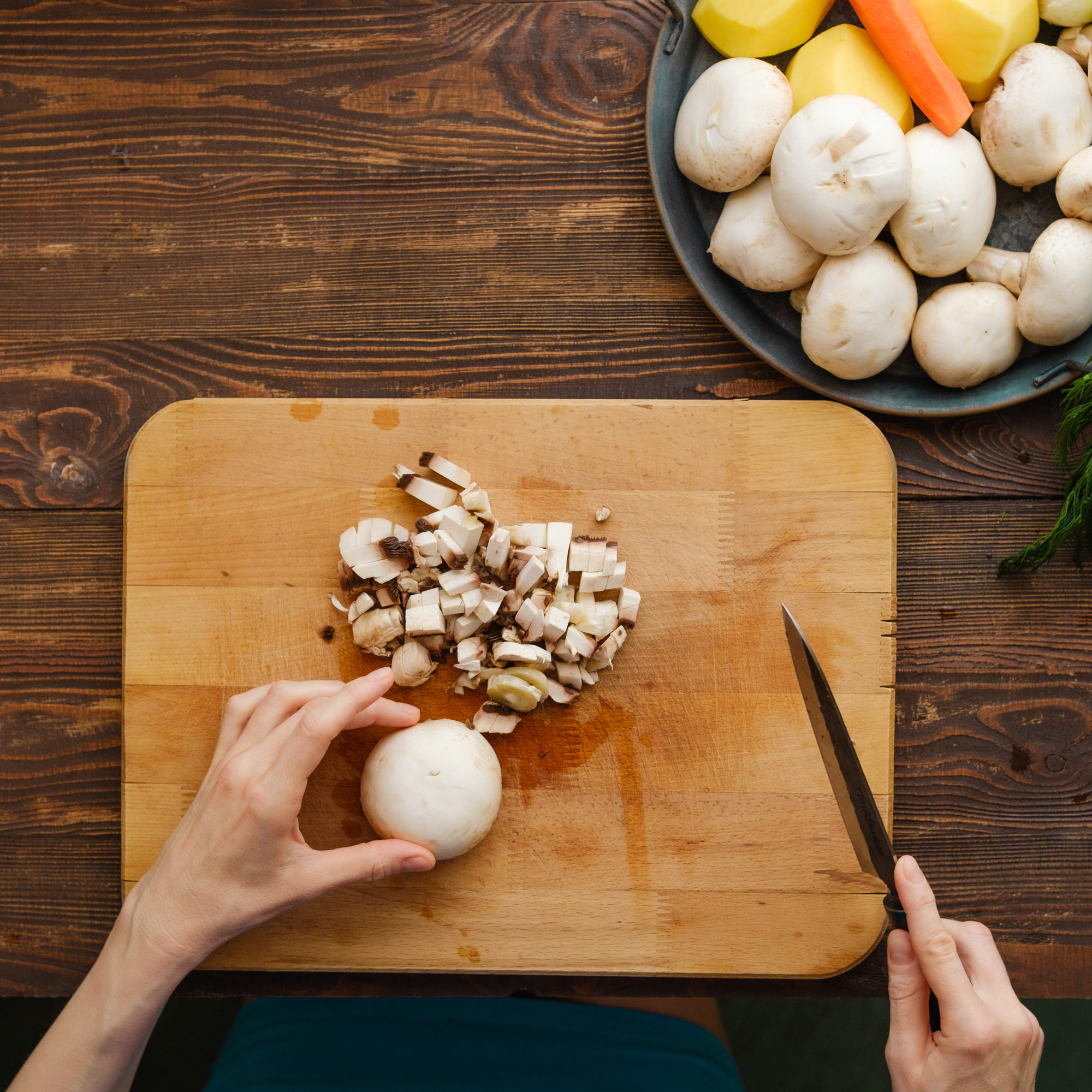 Unrecognizable woman chopping mushrooms, top view