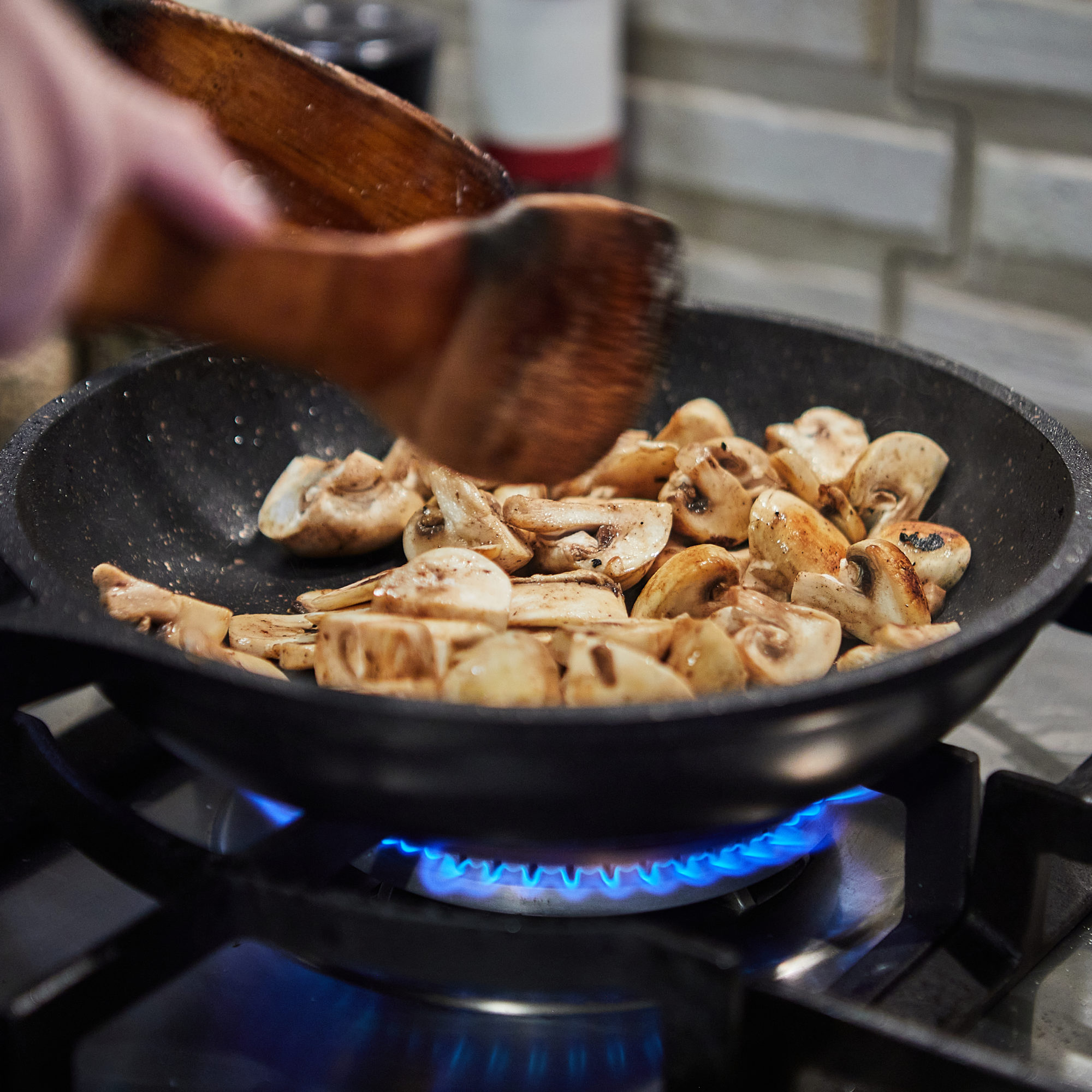 Chopped mushrooms are fried in frying pan on gas stove